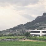 Bâtiment dans la verdure, avec vue sur les vignobles et la vallée de l'Adige.